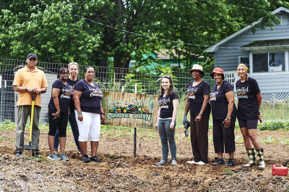 A-group-of-community-organizers-post-in-front-of-community-garden-sign