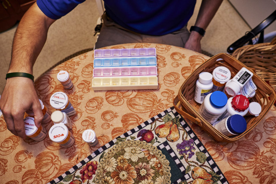 A health care provider organizes medications in a pill organizer