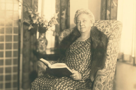 Kate B Reynolds sitting in a chair looking up while holding a book
