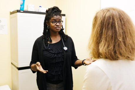 A health care provider explains to a patient with their arms open.